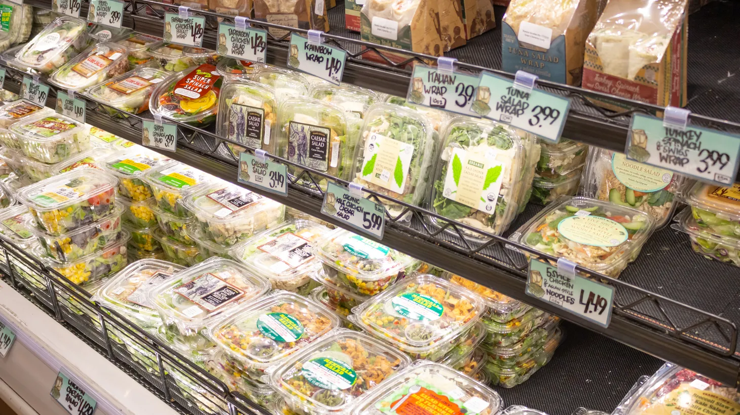 Premade salads in plastic containers line refrigerated shelves of a Trader Joe's in Los Angeles, California.