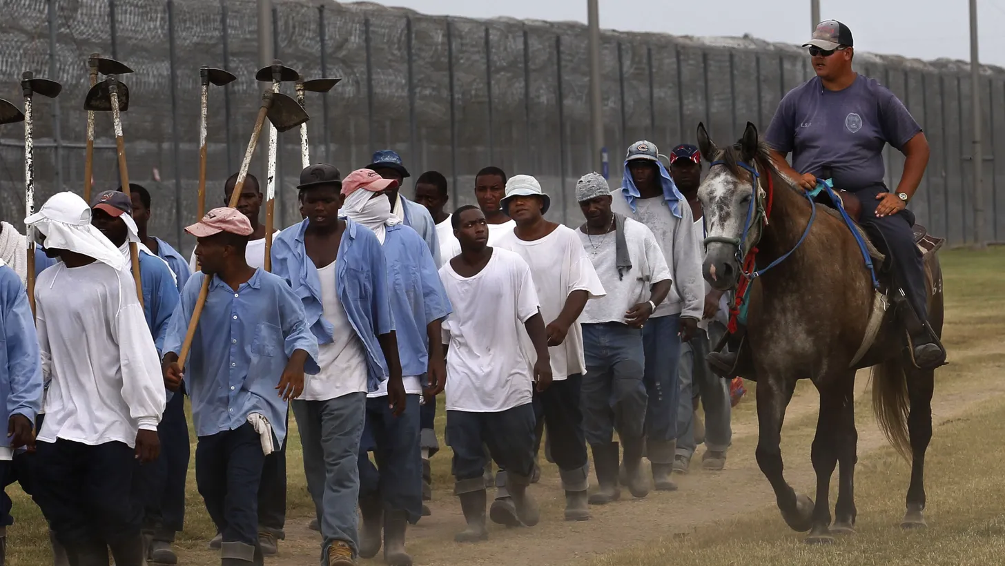 A prison guard rides a horse alongside prisoners as they return from farm work detail at the Louisiana State Penitentiary in Angola, Louisiana, on Aug. 18, 2011.