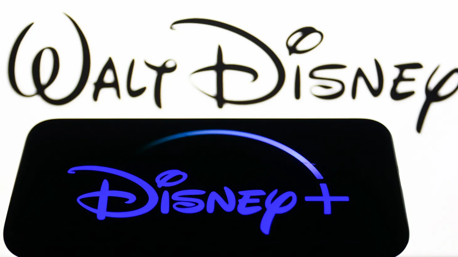 Disney+ logo displayed on a phone screen and The Walt Disney Company logo displayed on a screen are seen in this illustration photo taken in Krakow, Poland on August 20, 2022