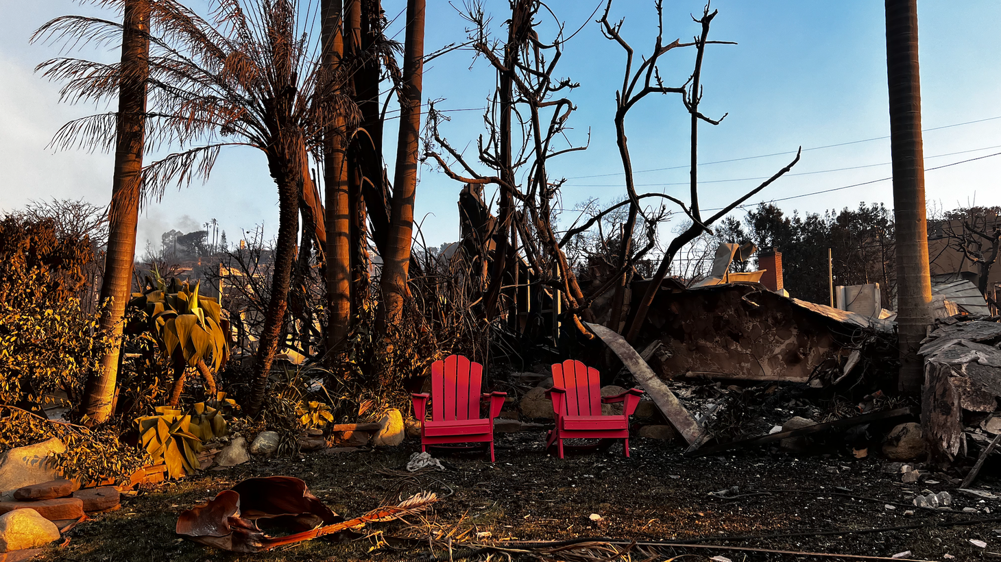 Two red chairs remain unscathed in the ruins of a yard in the Palisades.