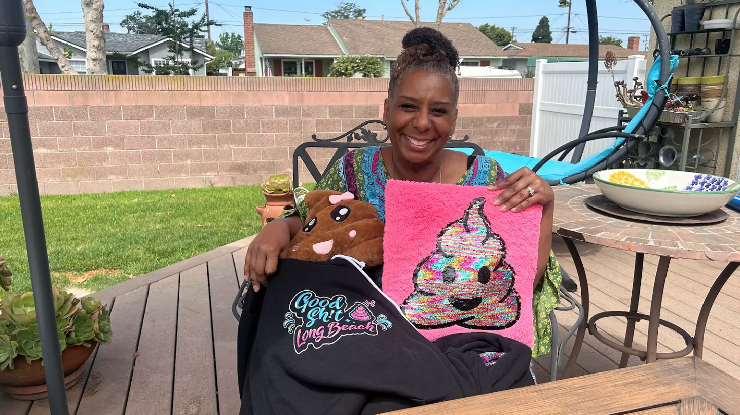 Tanya Cummings is the admin of Good Sh*t Long Beach. She created the glittery, pink poop emoji logo that adorns the merch she’s posing with.