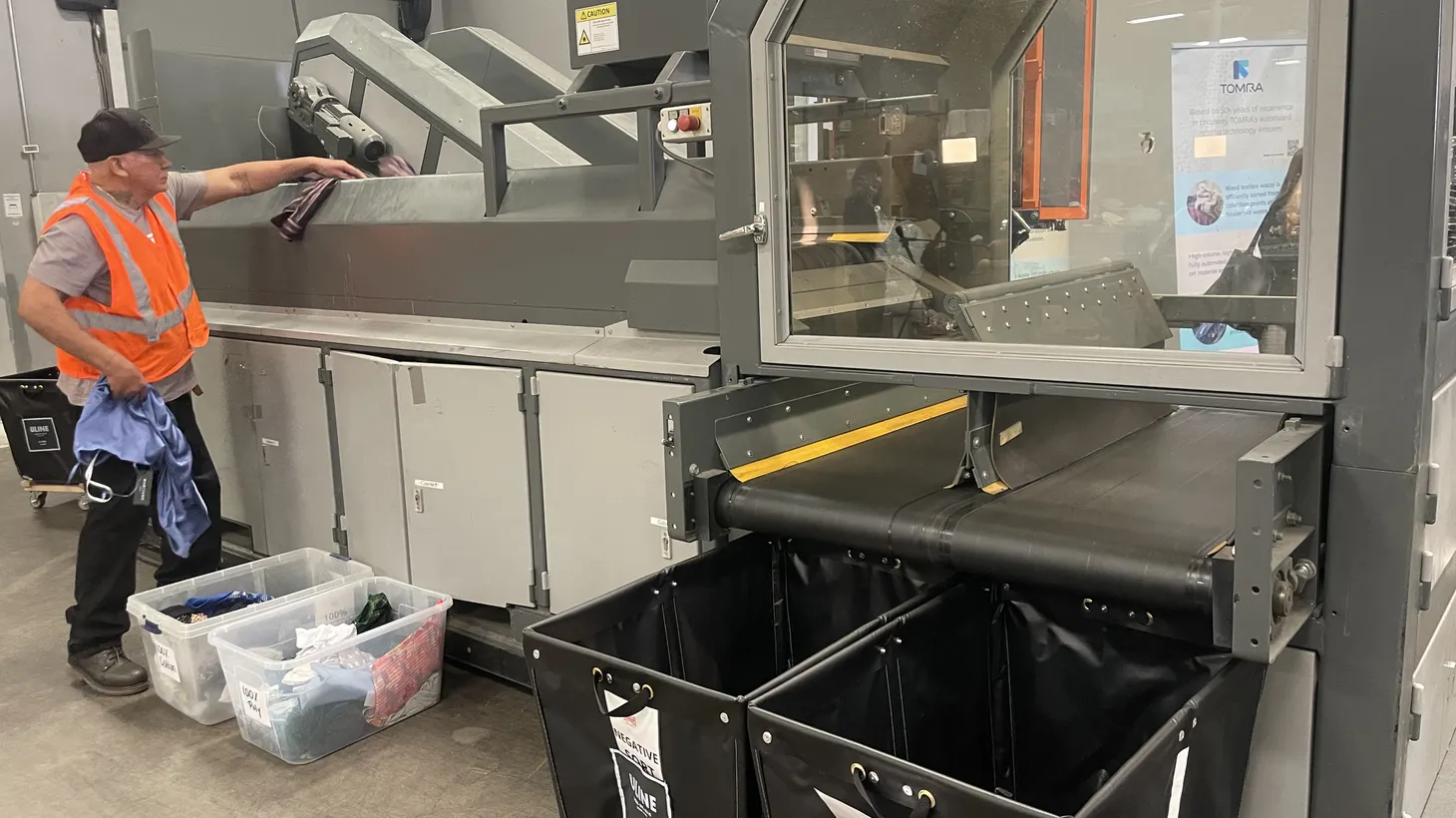 A recycler feeds clothes into a prototype machine that can sort textiles by fabric type at an event to showcase the new technology.