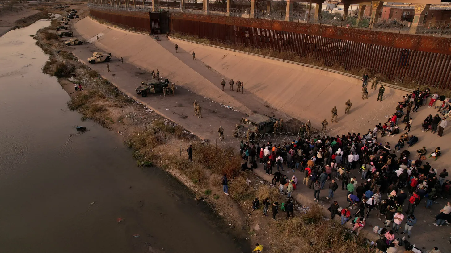 Migrants line up near the border wall after crossing the Rio Grande to turn themselves in to U.S. Border Patrol agents and request asylum in El Paso, Texas, seen from Juarez, Mexico, December 14, 2022.