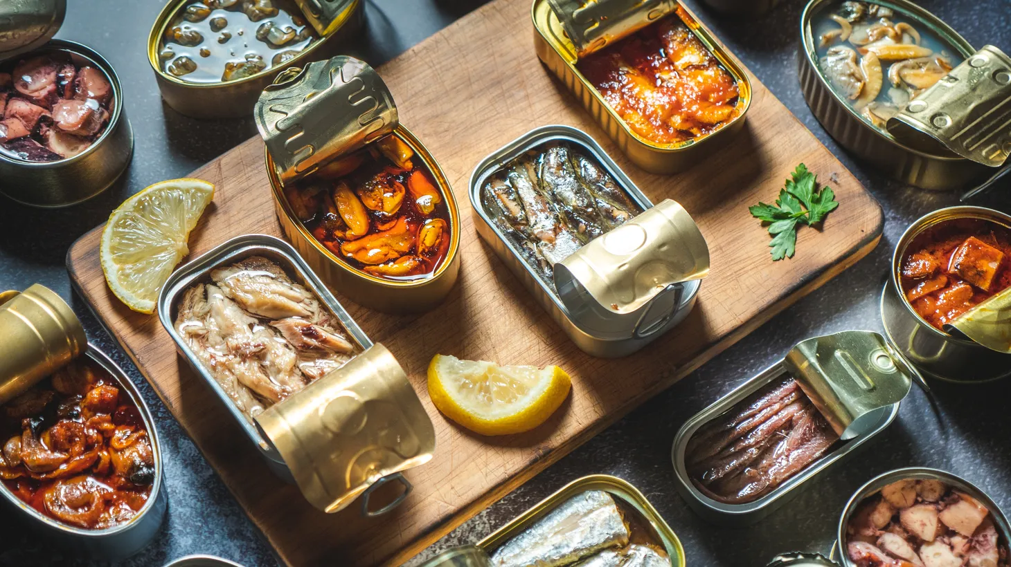 Assorted opened cans of fish and seafood are displayed on a counter.