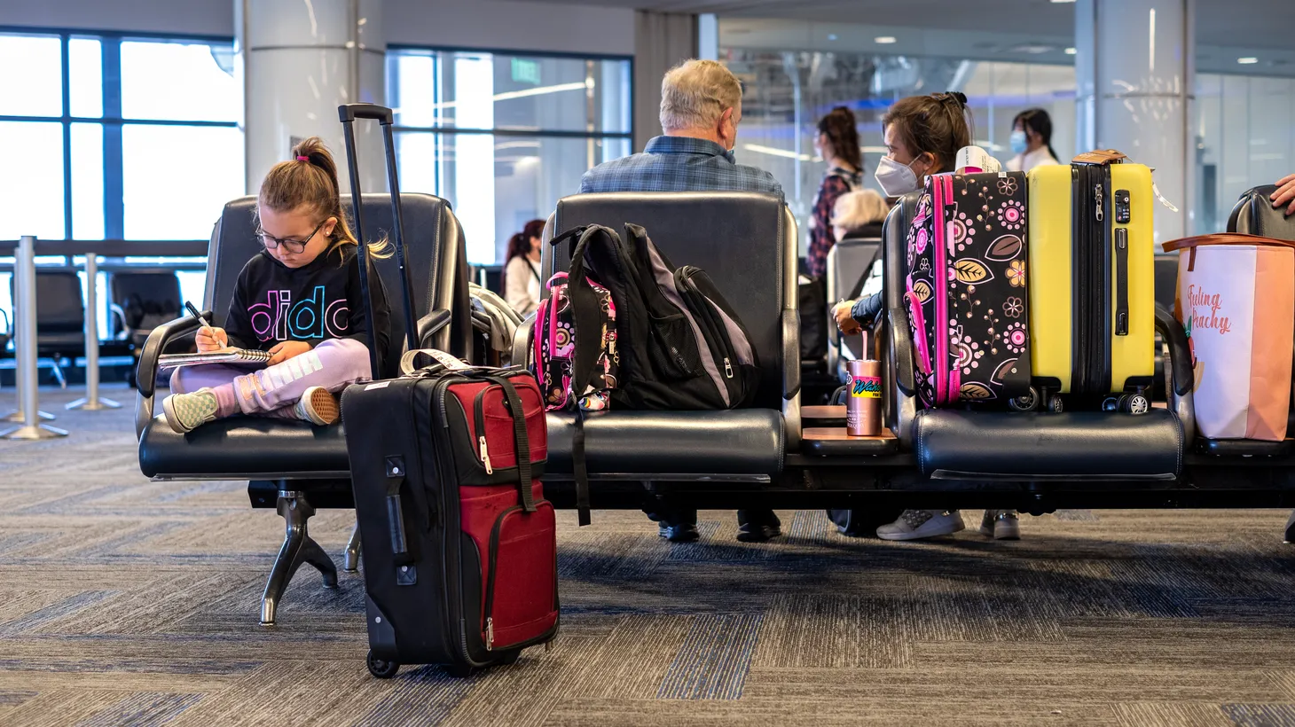A girl writes in her notebook in a waiting area at Los Angeles International Airport.