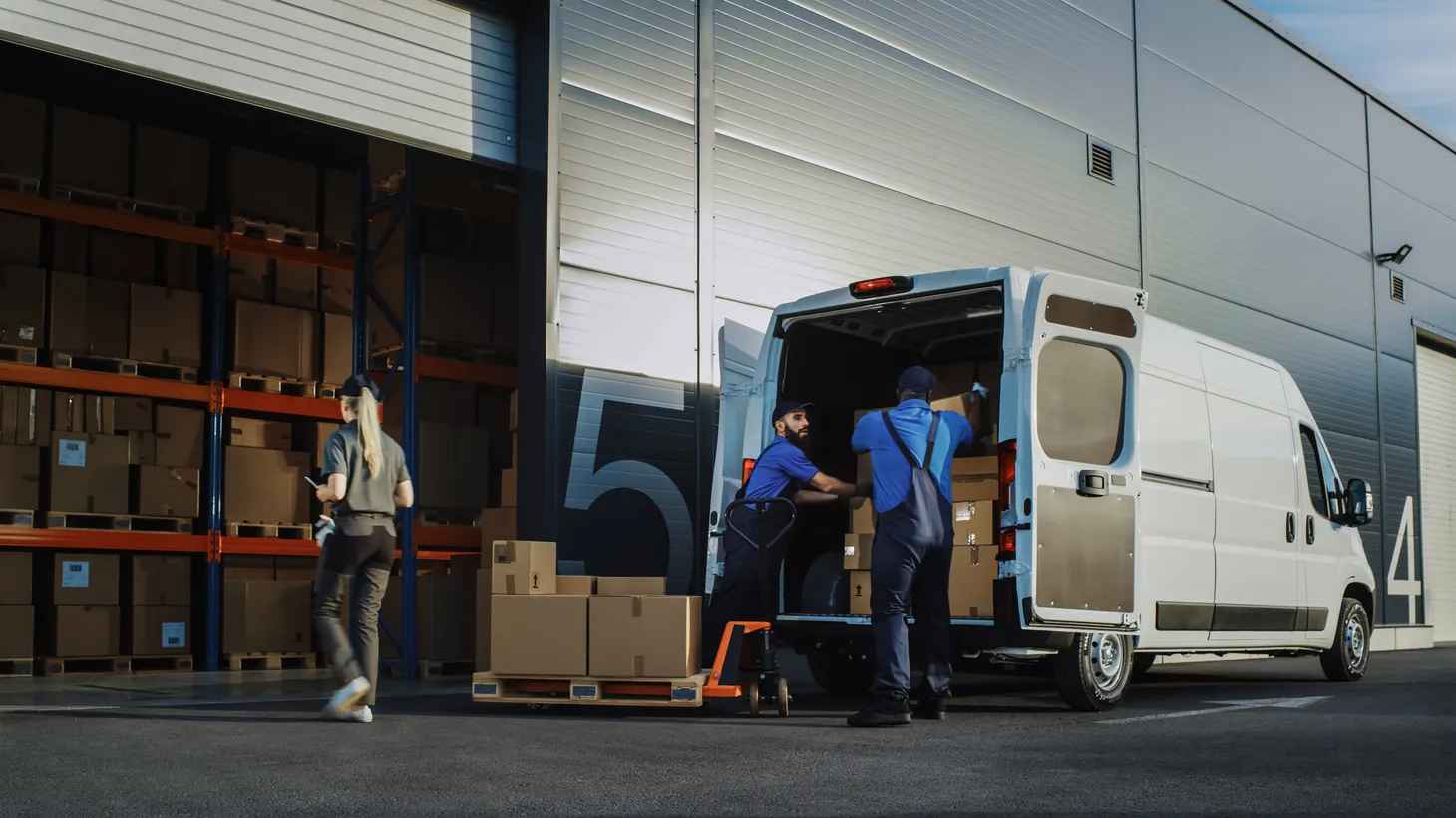 Workers unload new inventory boxes from a vehicle.