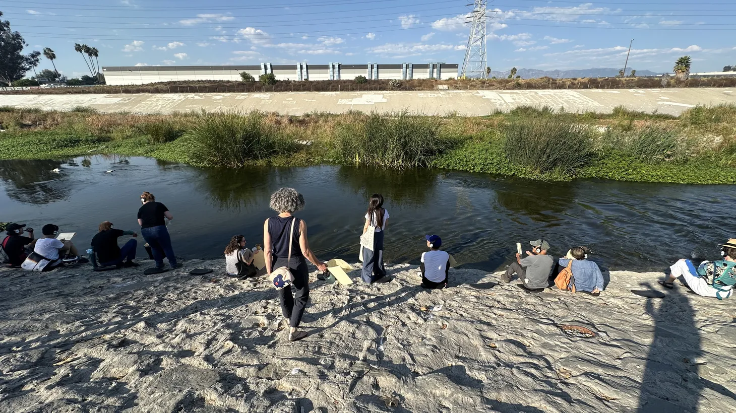 People wear headphones and sit along the edge of the LA River, just below the Glendale freeway in Frogtown, to immerse themselves in “What Water Wants.”