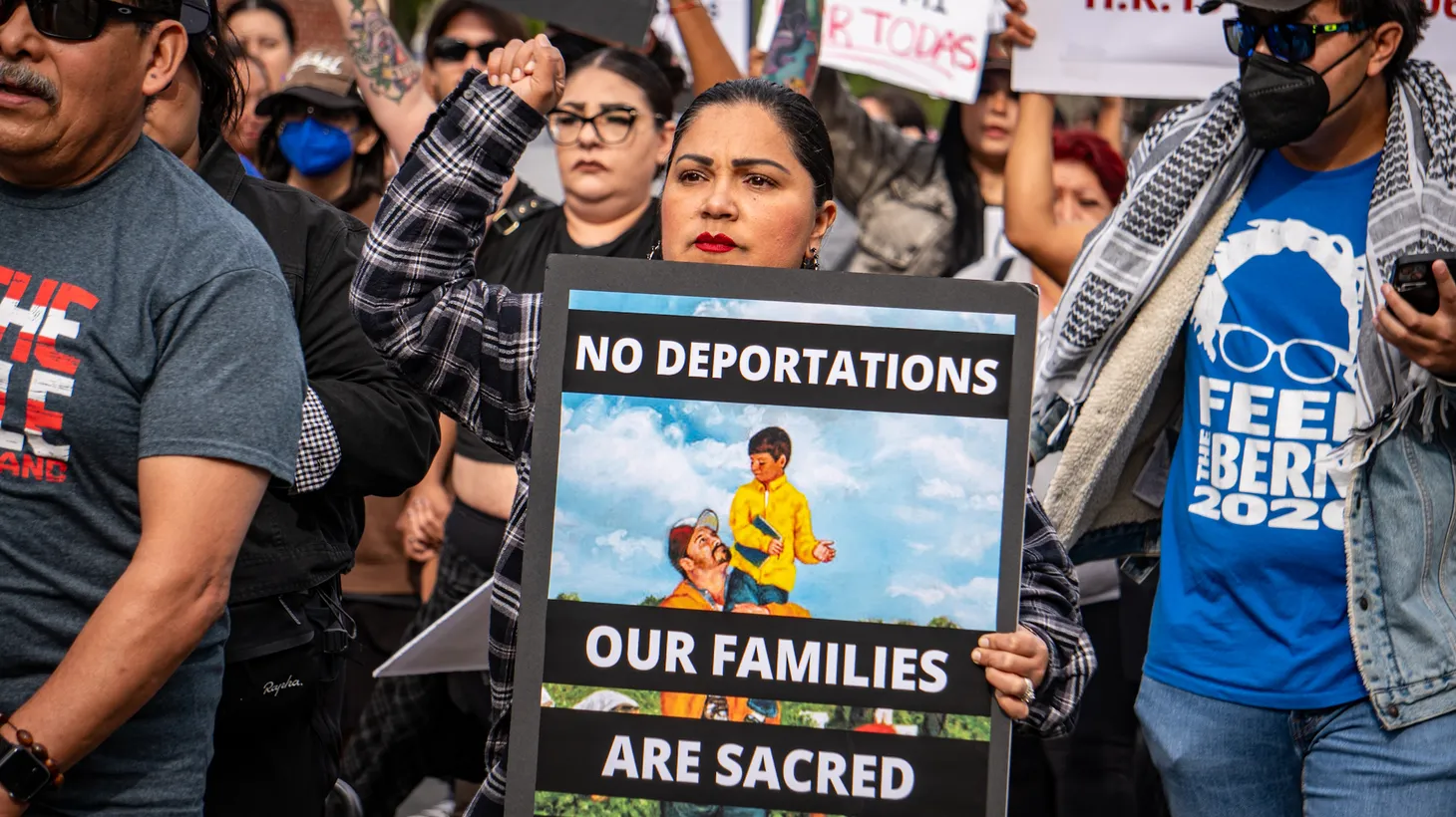 A woman holds a sign that says, “No deportations, our families are sacred, mass legalizations now,” at a rally at La Placita Olvera in Los Angeles, California, on November 11, 2024.