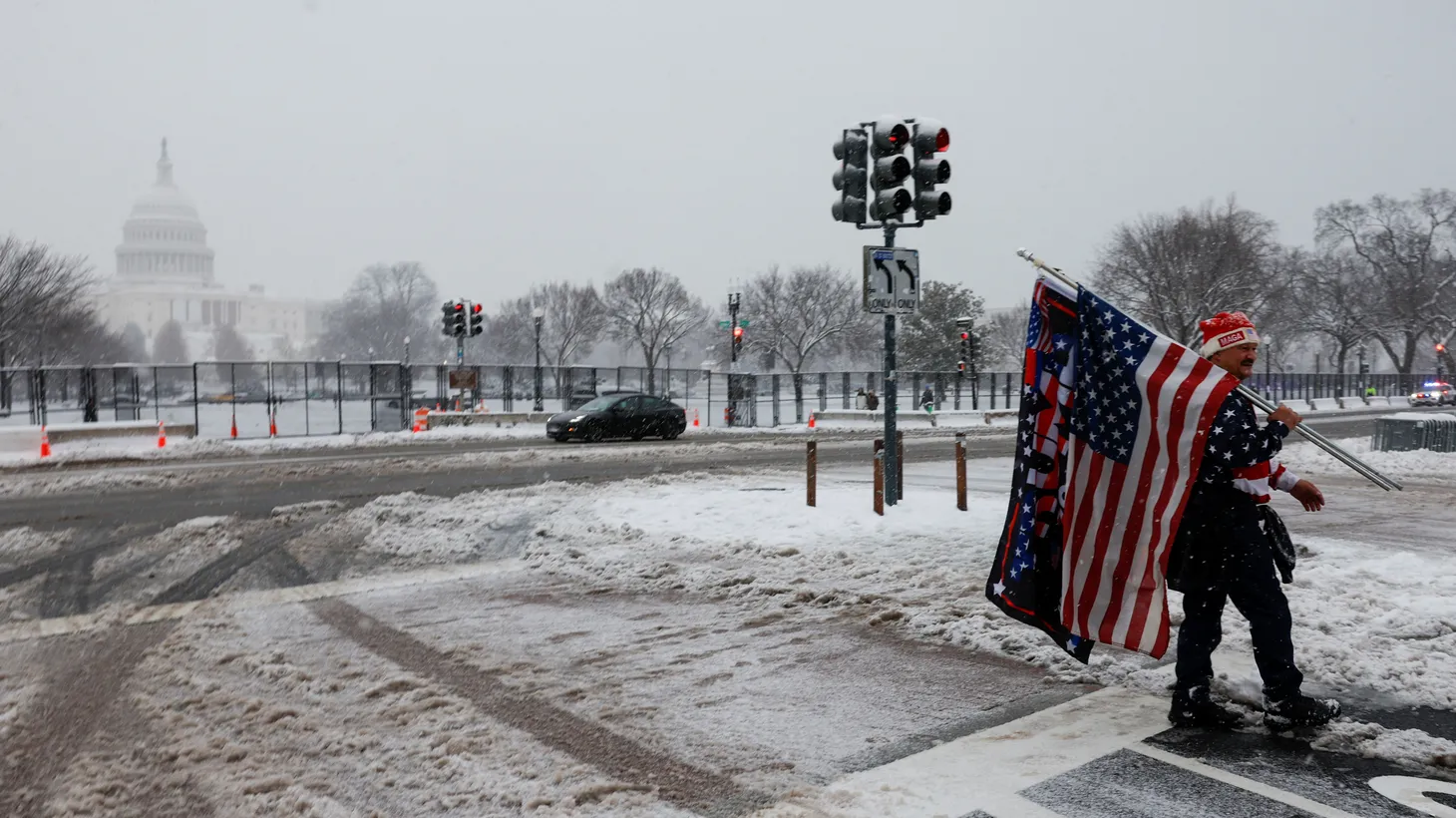 A supporter of U.S. President-elect Donald Trump holds flags and banners near the U.S. Capitol, on the day of a joint session of Congress to certify Donald Trump's election, as a winter storm arrived, in Washington, U.S. January 6, 2025.